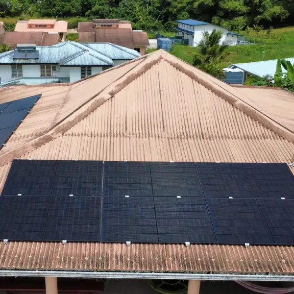Longue rangée de panneaux solaires sur toiture tôle saumon en Guyane