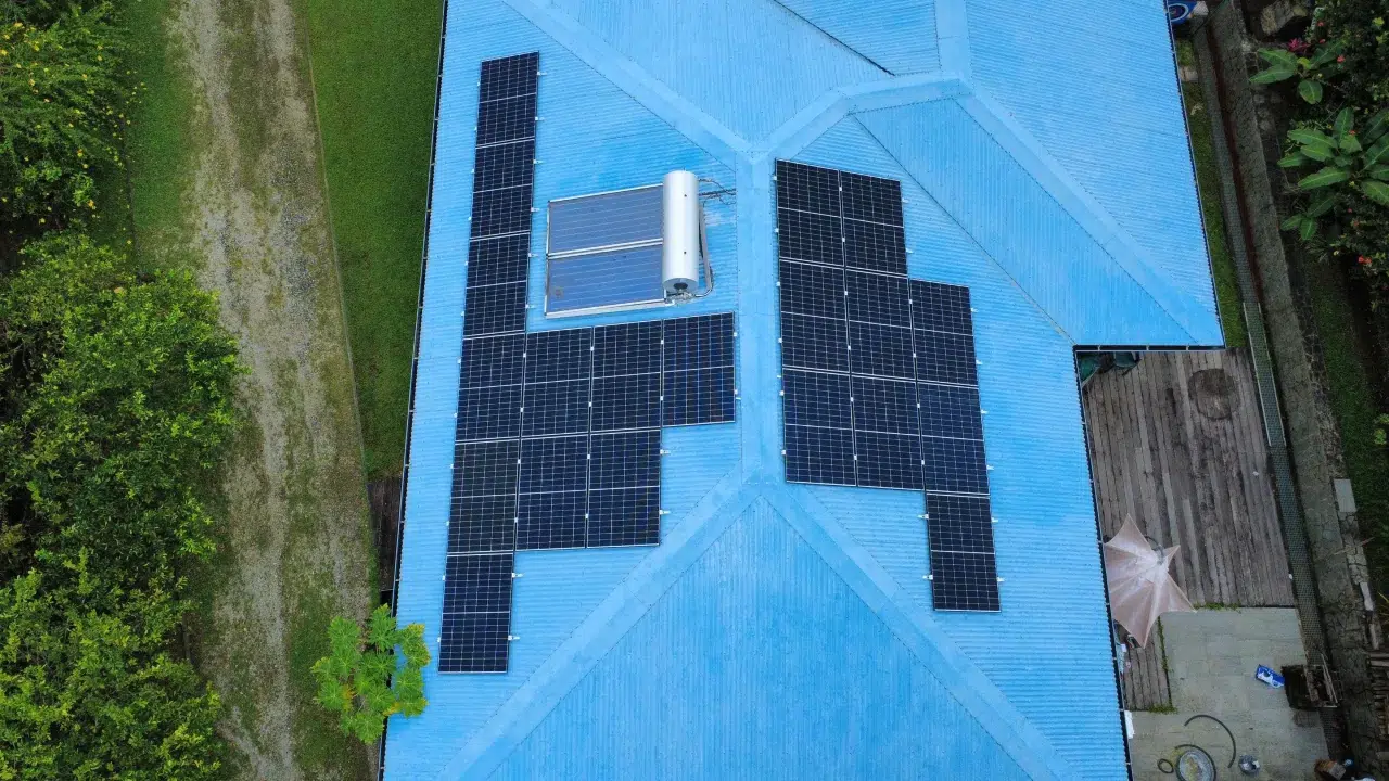 Panneaux solaires et chauffe-eau solaire sur une toiture bleue en Guyane