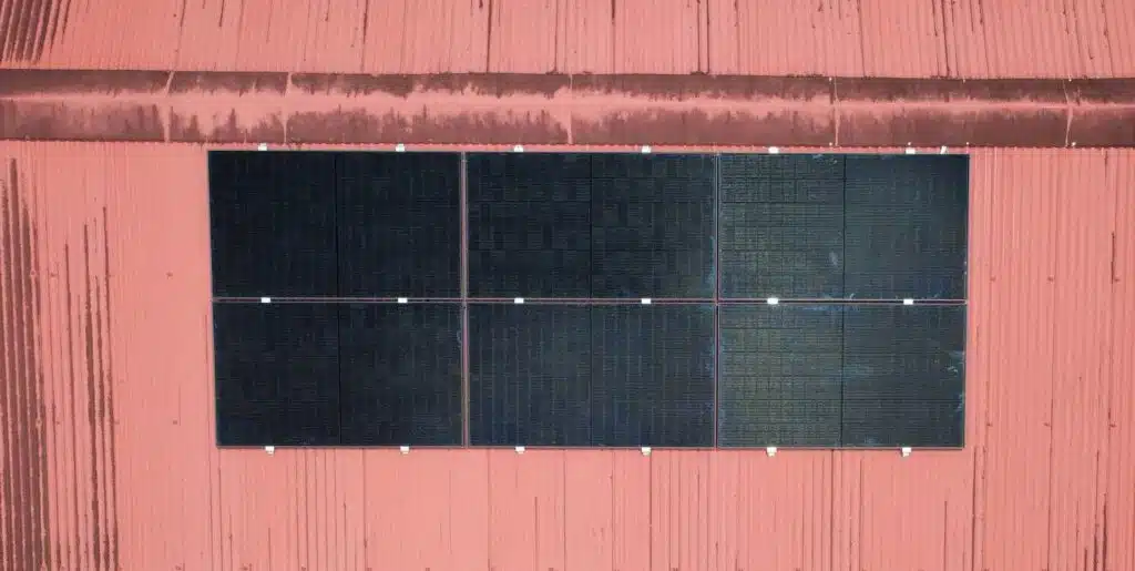 Six panneaux solaires photovoltaïques (3 kWc) posés en deux rangées sur une toiture en tôle rouge à Montsinéry-Tonnegrande, Guyane