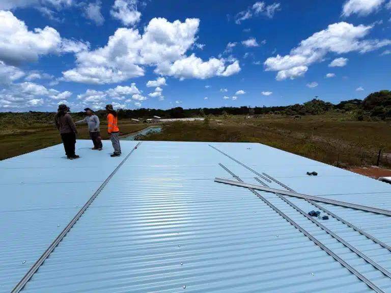Équipe de pose sur la toiture d’un site isolé en Guyane, rails de fixation en cours d’installation
